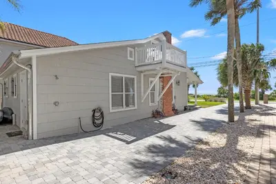 a house with a balcony and palm trees at Cute Beach Cottage Steps to the Beach! Panama City Beach, FL! in Panama City Beach