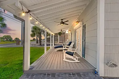 a porch with two chairs and a ceiling fan at Cute Beach Cottage Steps to the Beach! Panama City Beach, FL! in Panama City Beach