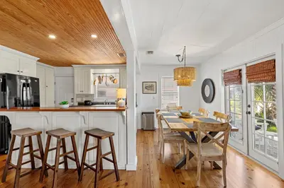 a kitchen with a table and stools in a room at Cute Beach Cottage Steps to the Beach! Panama City Beach, FL! in Panama City Beach