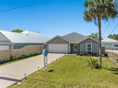 a house with a palm tree and a driveway at 3BD, 2BA Home! Family Friendly! Close to Beach! HOT TUB! in Panama City Beach