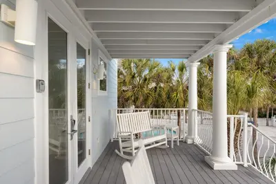 a white porch with a bench and palm trees at Book This Top Rated Luxury Home in Seagrove Now! Private Pool! in Santa Rosa Beach