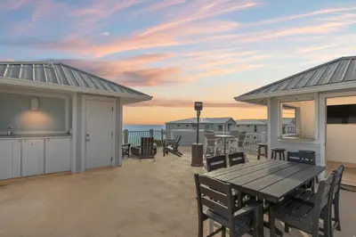 a patio with a wooden table and chairs and the ocean at Book This Top Rated Luxury Home in Seagrove Now! Private Pool! in Santa Rosa Beach