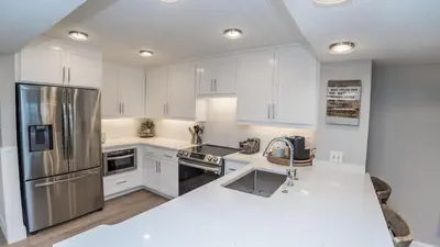 a kitchen with white cabinets and a stainless steel refrigerator at 5-STAR Beachfront - 2br & 2ba Total Remodel - Dunes of Panama D1105 in Panama City Beach