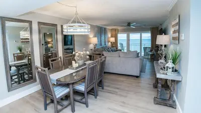 a dining room and living room with a table and chairs at 5-STAR Beachfront - 2br & 2ba Total Remodel - Dunes of Panama D1105 in Panama City Beach