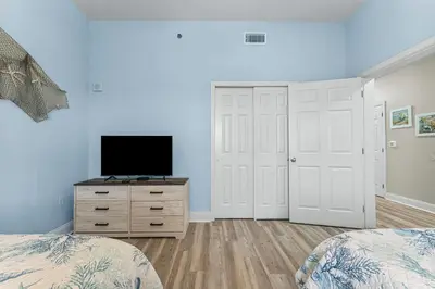 a bedroom with two beds and a television on a dresser at The Lost Flip Flop at Laketown Wharf #2012 by Nautical Properties in Panama City Beach