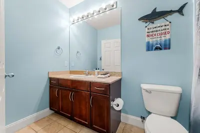 a bathroom with a sink and a shark sign on the wall at The Lost Flip Flop at Laketown Wharf #2012 by Nautical Properties in Panama City Beach