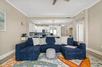 a living room with a blue couch and a kitchen at The Lost Flip Flop at Laketown Wharf #2012 by Nautical Properties in Panama City Beach