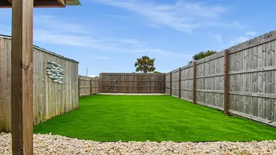 a backyard with a fence and green grass at Red Neptune by Nautical Properties in Panama City Beach
