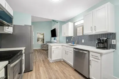 a kitchen with white cabinets and a refrigerator at Red Neptune by Nautical Properties in Panama City Beach