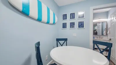 a bathroom with a white toilet and a surfboard on the wall at Red Neptune by Nautical Properties in Panama City Beach