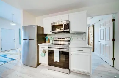 a kitchen with white cabinets and a stainless steel refrigerator at Lagoon 2621 by Nautical Properties in Panama City Beach