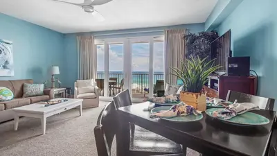 a living room with a dining room table with a view of the ocean at The Tide View at Laketown Wharf #904 by Nautical Properties in Panama City Beach