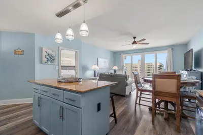 a kitchen and living room with blue walls and a table at Beachy King at Laketown Wharf #812 by Nautical Properties in Panama City Beach