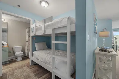 a bedroom with a bunk bed and a bathroom at Beachy King at Laketown Wharf #812 by Nautical Properties in Panama City Beach