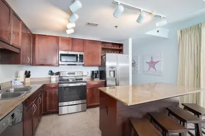 a kitchen with wooden cabinets and stainless steel appliances at Bikini Bottom at Laketown Wharf #501 by Nautical Properties in Panama City Beach