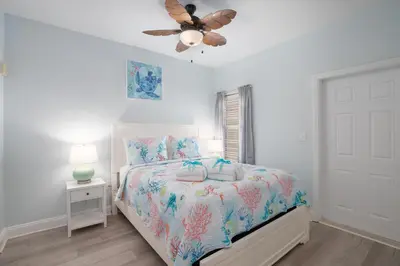 a white bedroom with a bed and a ceiling fan at Bikini Bottom at Laketown Wharf #501 by Nautical Properties in Panama City Beach