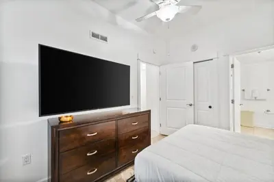 a bedroom with a flat screen tv on a white wall at Grand Panama #2-1307 in Panama City Beach
