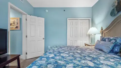 a blue bedroom with a bed and a television at Sunsational at Laketown Wharf #1924 by Nautical Properties in Panama City Beach