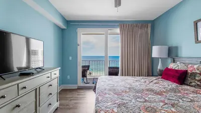 a bedroom with a bed with a television and a balcony at Sunsational at Laketown Wharf #1924 by Nautical Properties in Panama City Beach