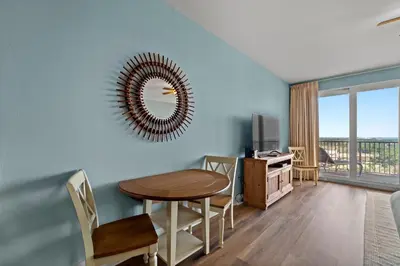 a living room with a table and a mirror at Deja Blue at Laketown Wharf #1831 by Nautical Properties in Panama City Beach