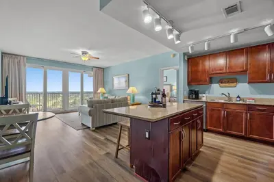 a kitchen with wooden cabinets and a living room at Deja Blue at Laketown Wharf #1831 by Nautical Properties in Panama City Beach