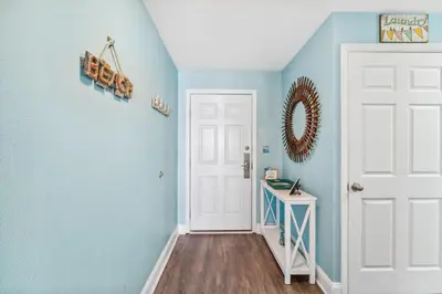 a hallway with blue walls and a white door at Sea-Renity at Laketown Wharf #1607 by Nautical Properties in Panama City Beach