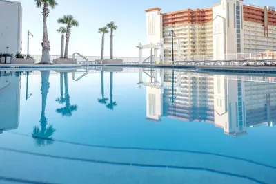 a pool of blue water with palm trees and buildings at Sea-Renity at Laketown Wharf #1607 by Nautical Properties in Panama City Beach