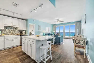 a kitchen with white cabinets and a view of the ocean at Sea-Renity at Laketown Wharf #1607 by Nautical Properties in Panama City Beach