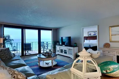 a living room with a couch and a room with a balcony at Edgewater Tower Iii 612 in Panama City Beach