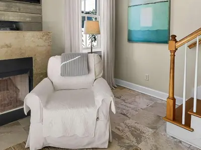 a living room with a chair and a fireplace at Beach Music in Rosemary Beach