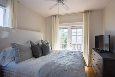 a bedroom with a bed with pillows and a television at Beach Music in Rosemary Beach