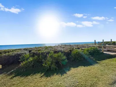 a fence on a beach with the ocean in the background at Beach Music in Rosemary Beach