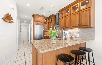 a kitchen with wooden cabinets and a island with bar stools at Front Row in Inlet Beach