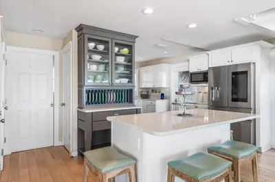 a kitchen with white cabinets and a counter with stools at Kokomo in Santa Rosa Beach