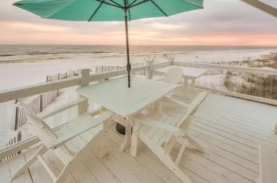 a table and chairs on a deck with an umbrella at Kokomo in Santa Rosa Beach