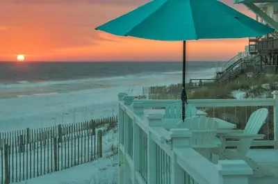 a table and chairs with an umbrella on the beach at Kokomo in Santa Rosa Beach