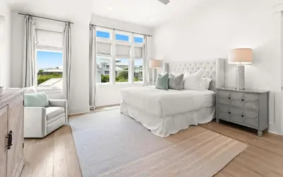 a white bedroom with a bed and a chair at SEAcret to Life in Inlet Beach