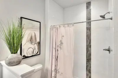 a white bathroom with a shower and a vase with a plant at Rosie Disposition in Santa Rosa Beach