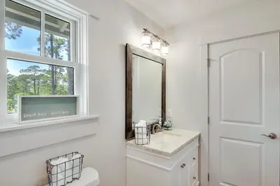 a bathroom with a toilet and a mirror and a window at Rosie Disposition in Santa Rosa Beach