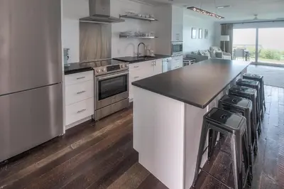 a kitchen with white cabinets and a black counter top at The Good Life in Inlet Beach