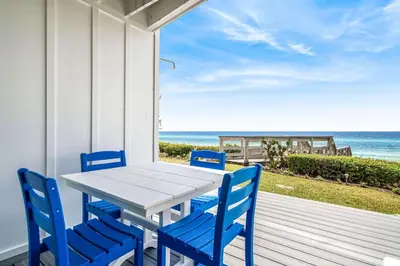 a table and chairs on a porch with the beach at The Good Life in Inlet Beach