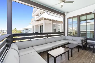 a living room with a couch and tables on a balcony at Moonstruck in Santa Rosa Beach