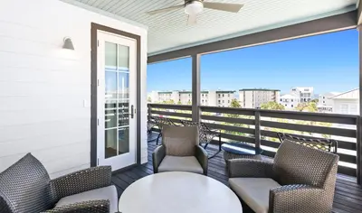 a balcony with chairs and a table and a window at Moonstruck in Santa Rosa Beach