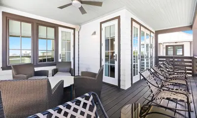 a screened porch with wicker chairs and windows at Moonstruck in Santa Rosa Beach