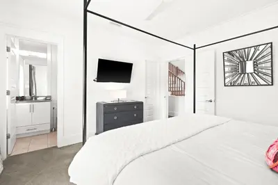 a white bedroom with a bed and a tv at Moonstruck in Santa Rosa Beach