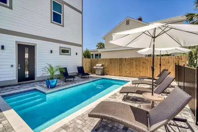 a swimming pool with chairs and an umbrella at The Sundowner in Panama City Beach