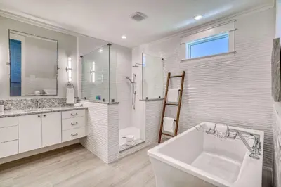 a white bathroom with a large tub and a sink at The Sundowner in Panama City Beach