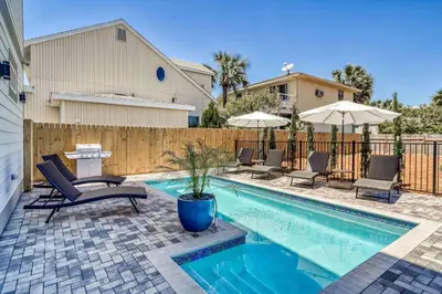 a swimming pool with chairs and umbrellas next to a fence at The Sundowner in Panama City Beach