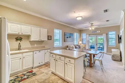 a kitchen with white cabinets and a table in a room at Saltwater Dreams in Santa Rosa Beach