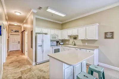 a kitchen with white cabinets and a white refrigerator at Saltwater Dreams in Santa Rosa Beach